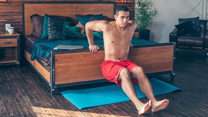 Man doing sitting push-ups on his bed frame