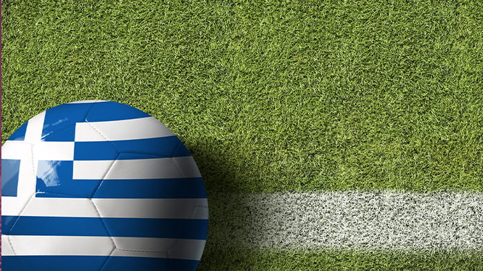 A Greek flag soccer ball on the white line of a soccer field