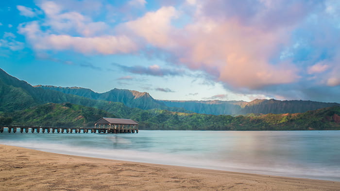 Hanalei Bay beach with its pier and mountains in the background