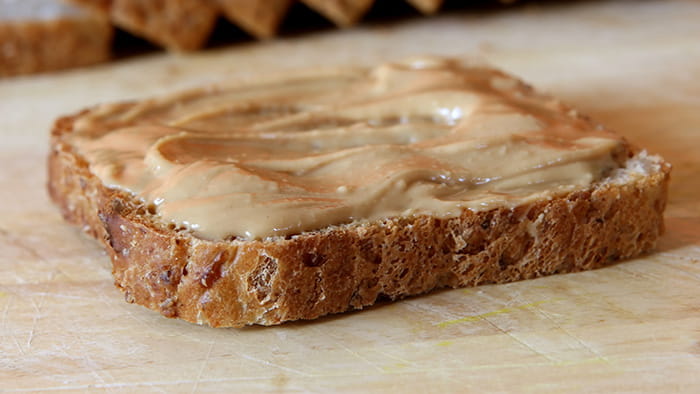 A perfectly square slice of peanut butter placed on a slice of bread