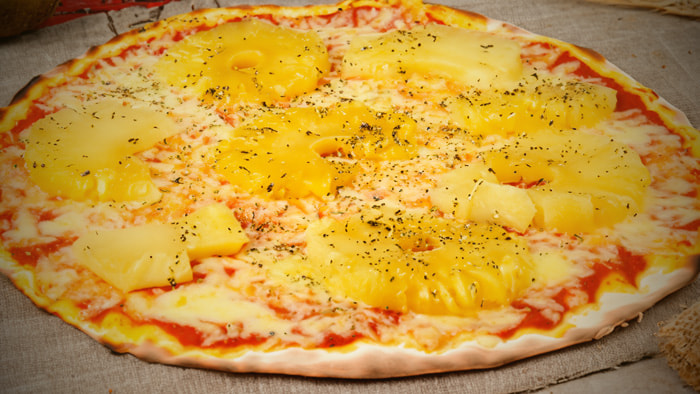 A delicious slice of Hawaiian pizza with melted cheese, ham, and pineapple chunks.