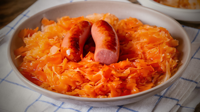 A serving of sauerkraut, showcasing its fermented strands and slight tanginess, paired perfectly with a German sausage.