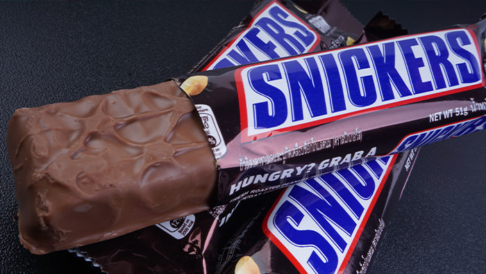 A Snickers bar showcasing its layers of nougat, caramel, and nuts